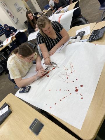 Two students measuring blood splatter